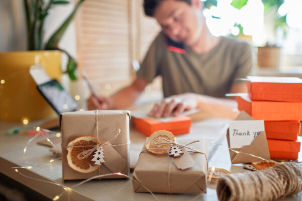 Worker on phone while wrapping holiday gifts