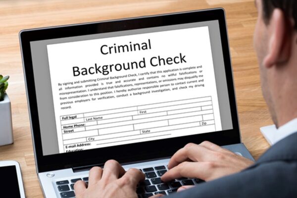 Person using a laptop to fill out a criminal background check form, representing employment screening for individuals with prior criminal records.